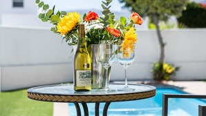 Una mesa redonda con una botella de vino, dos copas de vino y un arreglo floral.