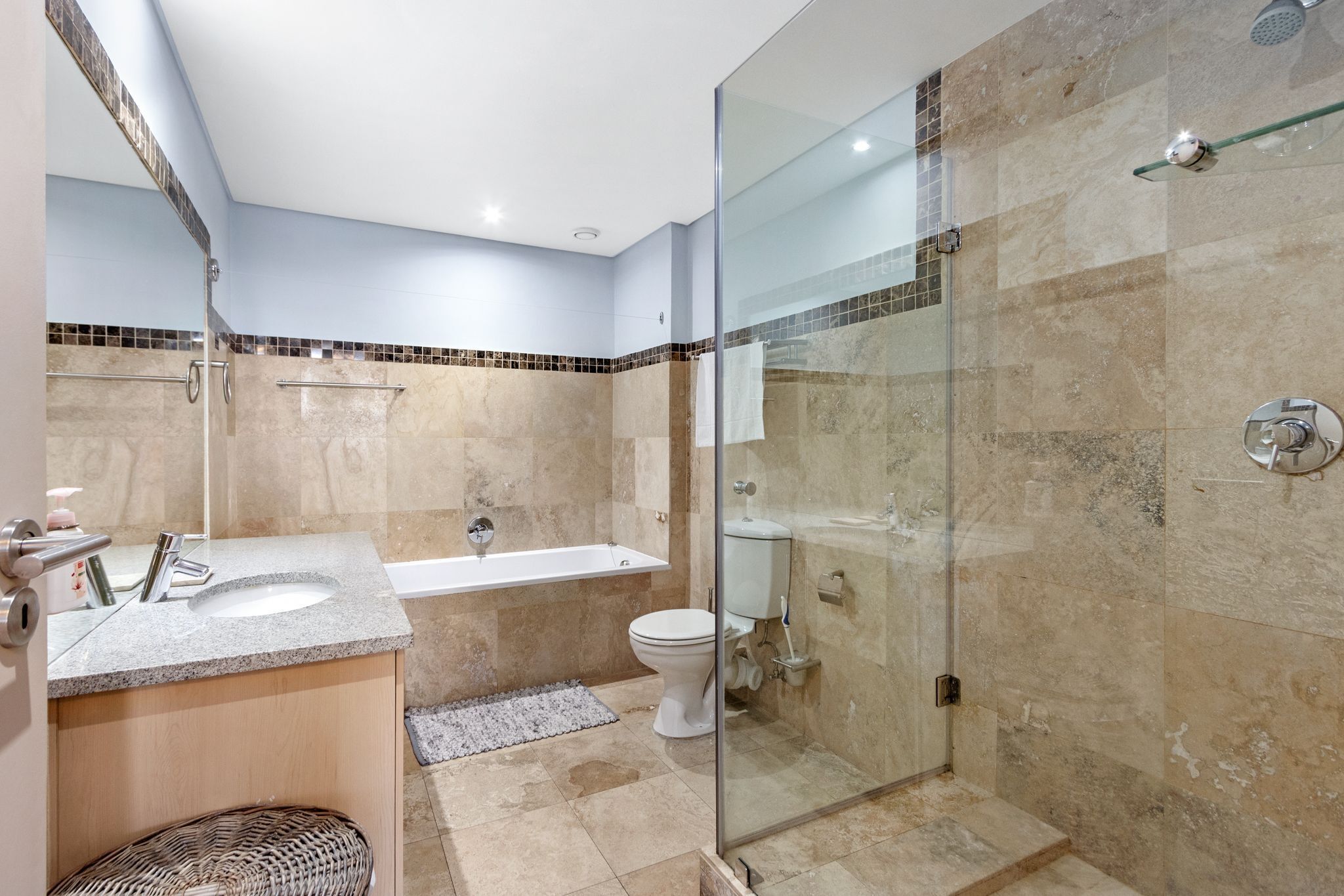 A modern bathroom with a glass-enclosed shower, a bathtub, and a toilet.