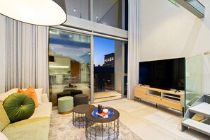 A modern living room with a sofa, ottomans, a coffee table, a TV, and a glass door leading to a balcony. - Apartment 307 at 117 on Strand (Cape Town)