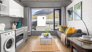 Un espacio habitable compacto con cocina, sofá, mesa de centro y vistas a la montaña.