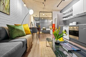 A modern living room with a grey sofa, colorful cushions, a glass coffee table, and a potted plant. - The Wex 620 (Cape Town)
