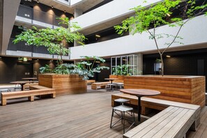 A spacious outdoor area with wooden benches, tables, and planters. - The Wex 620 (Cape Town)