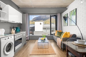A compact living space with a kitchen, a sofa, a coffee table, and a view of a mountain. - The Wex 620 (Cape Town)