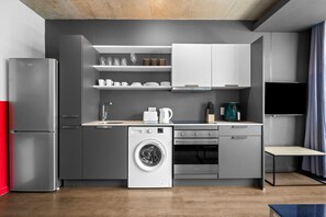 A compact kitchen with a built-in washer and dryer, a refrigerator, and a flat-screen TV. - The Wex 620 (Cape Town)