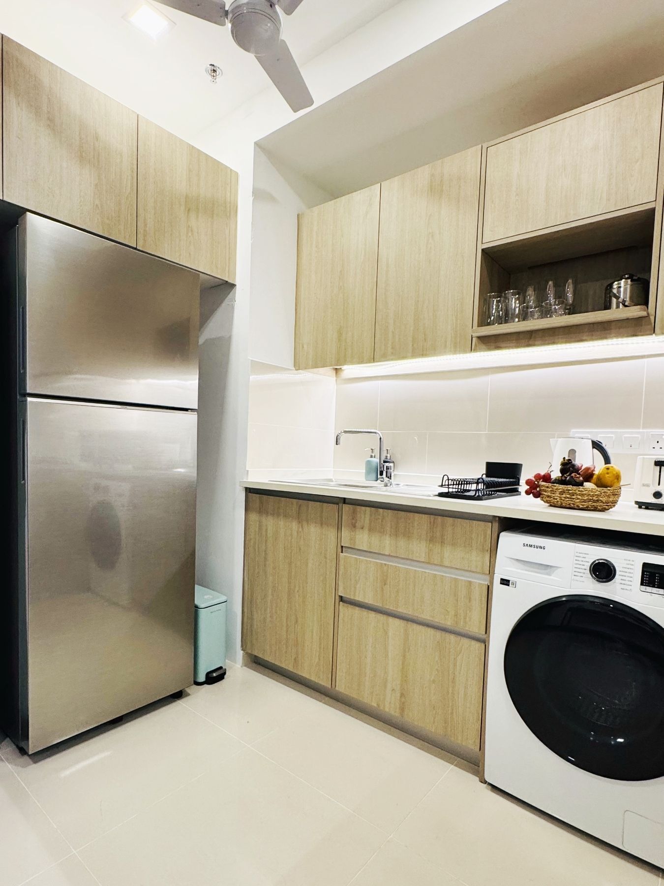 A modern kitchen with stainless steel appliances, wooden cabinets, and a built-in washing machine.