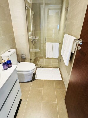 A bathroom with a toilet, sink, and shower. - YAKA Trizen Luxury Apartments (Colombo)