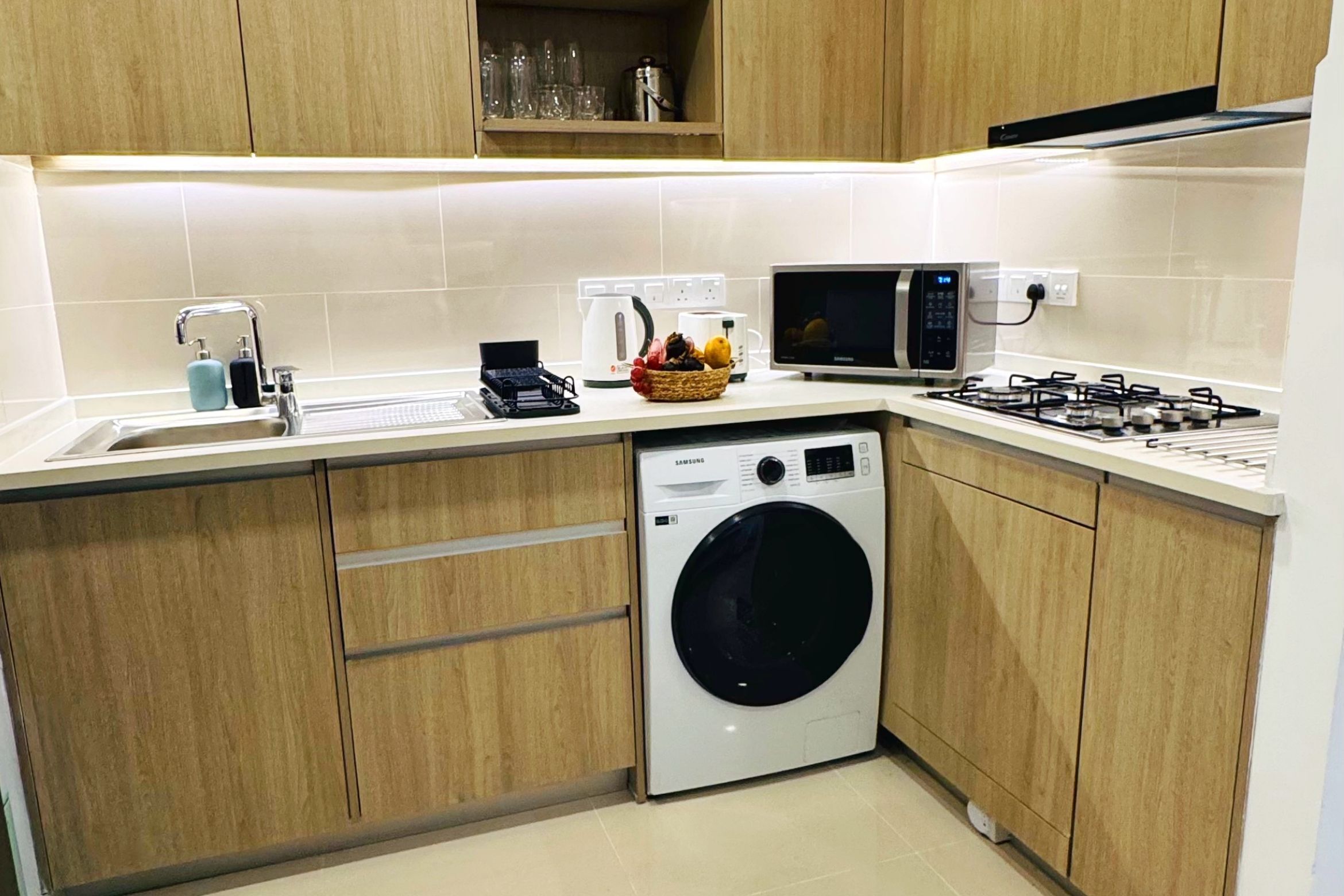 A compact kitchen with a washing machine, microwave, and gas stove.