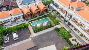 Vista aérea de un hotel con varias cabañas, una piscina y un estacionamiento.