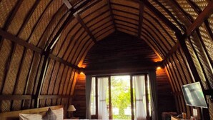 An inn room with a wooden ceiling, a large bed, a desk with a chair, and a TV. - MAILAKU HOUSE (Kerobokan Kaja)
