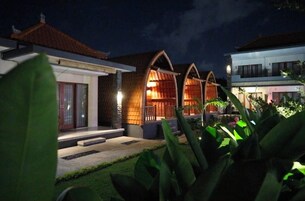 A traditional house with a tiled roof, a wooden porch, and a well-lit interior.