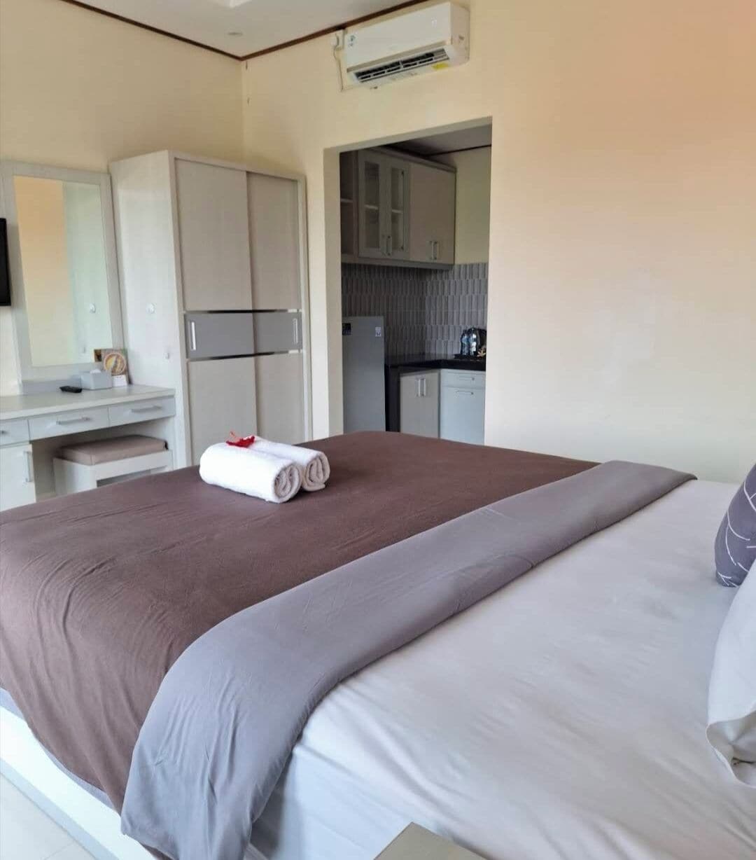 A hotel room with a bed, a desk, and a kitchenette.