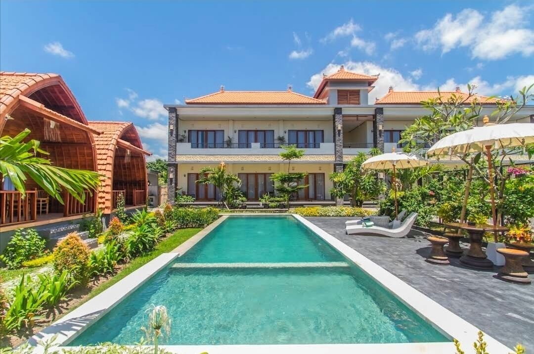 Un hotel grande y moderno con piscina, jardines exuberantes y un estilo arquitectónico tradicional.