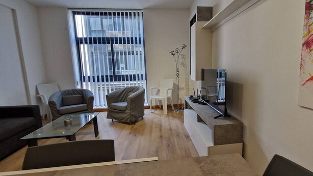 A modern living room with a sofa, armchairs, a coffee table, a TV, and a painting on the wall. - Centrally located in Sliema, this apartment puts you steps from shops, restaurants, cafés, and the lively promenade (Tas-Sliema)