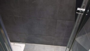 A bathroom with a glass shower door, tiled walls, and a white floor. - Centrally located in Sliema, this apartment puts you steps from shops, restaurants, cafés, and the lively promenade (Tas-Sliema)