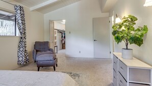 A bedroom with a bed, a grey armchair, a dresser, a potted plant, and a hallway leading to a closet. - Wfh-friendly Retreat < 1 Mi to Clear Lake! (Kelseyville)