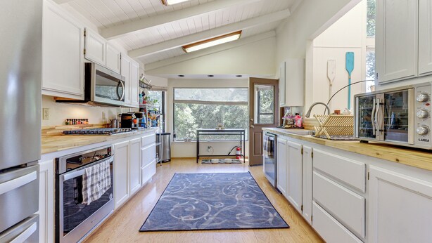 A modern kitchen with white cabinets, stainless steel appliances, and a large window providing natural light. - Wfh-friendly Retreat < 1 Mi to Clear Lake! (Kelseyville)