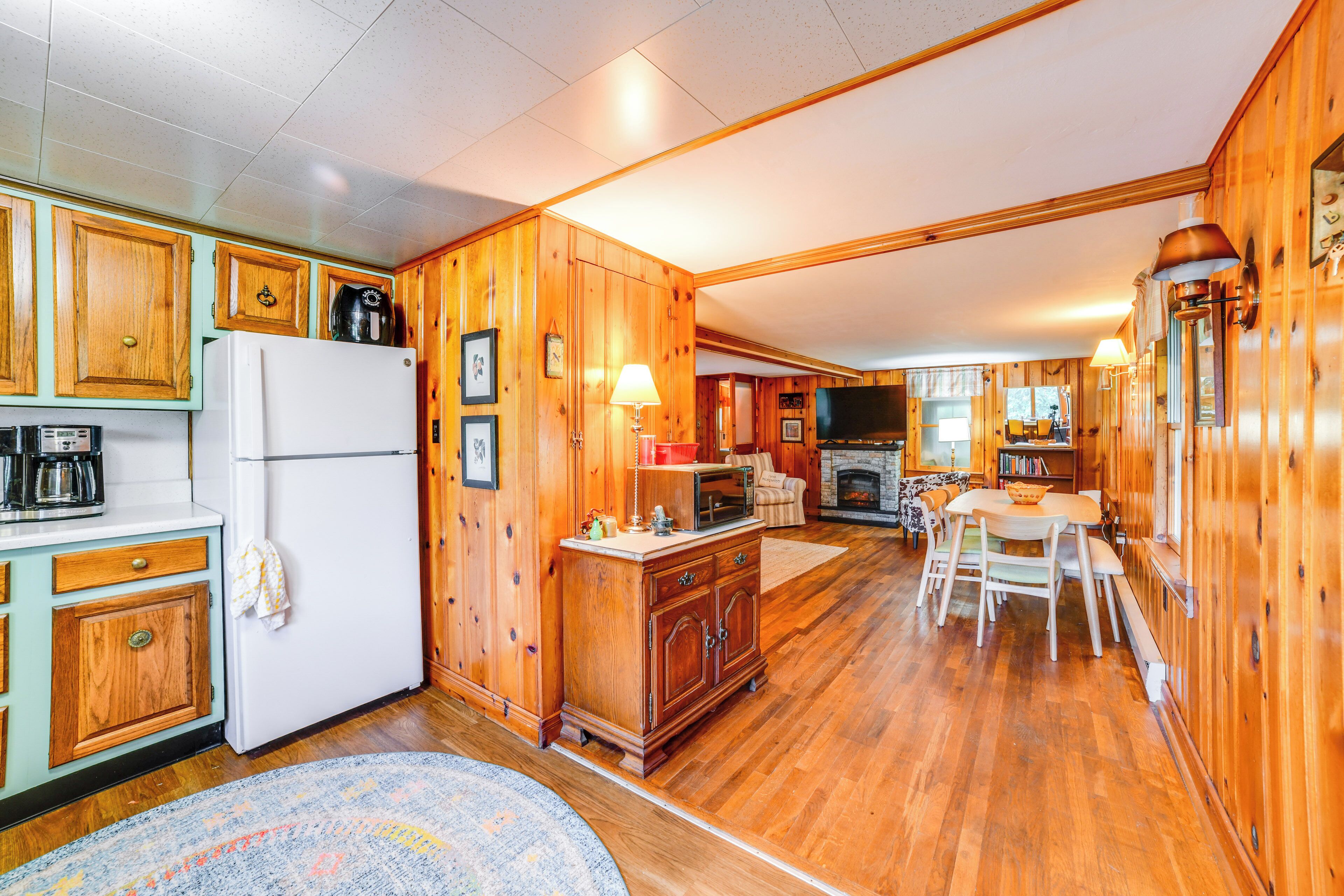 A wooden cabin interior with a kitchen, dining area, and fireplace.