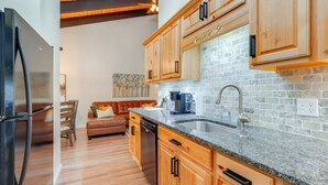 Eine moderne Küche mit Holzschränken, einer Granitarbeitsplatte und einem Edelstahlkühlschrank.