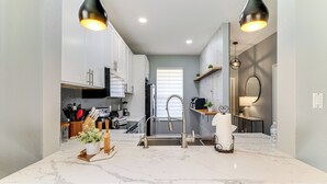 Una cocina moderna con encimeras de mármol, electrodomésticos de acero inoxidable e iluminación colgante.