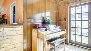 A piano in a room with wooden paneling and a door with a window. - Private Yard w/ Pool: Quiet Getaway in San Antonio (San Antonio)