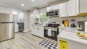 Cocina moderna con armarios blancos, electrodomésticos de acero inoxidable y un tapete de pisos a cuadros.
