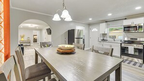 Una cocina moderna con armarios blancos, electrodomésticos de acero inoxidable y una mesa de comedor de madera con sillas.