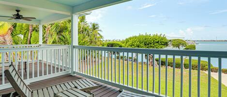 A covered outdoor deck with wooden furniture and a view of the ocean.
