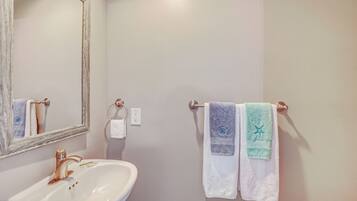 Un baño con un lavamanos blanco, un espejo y dos toallas colgadas en un toallero.