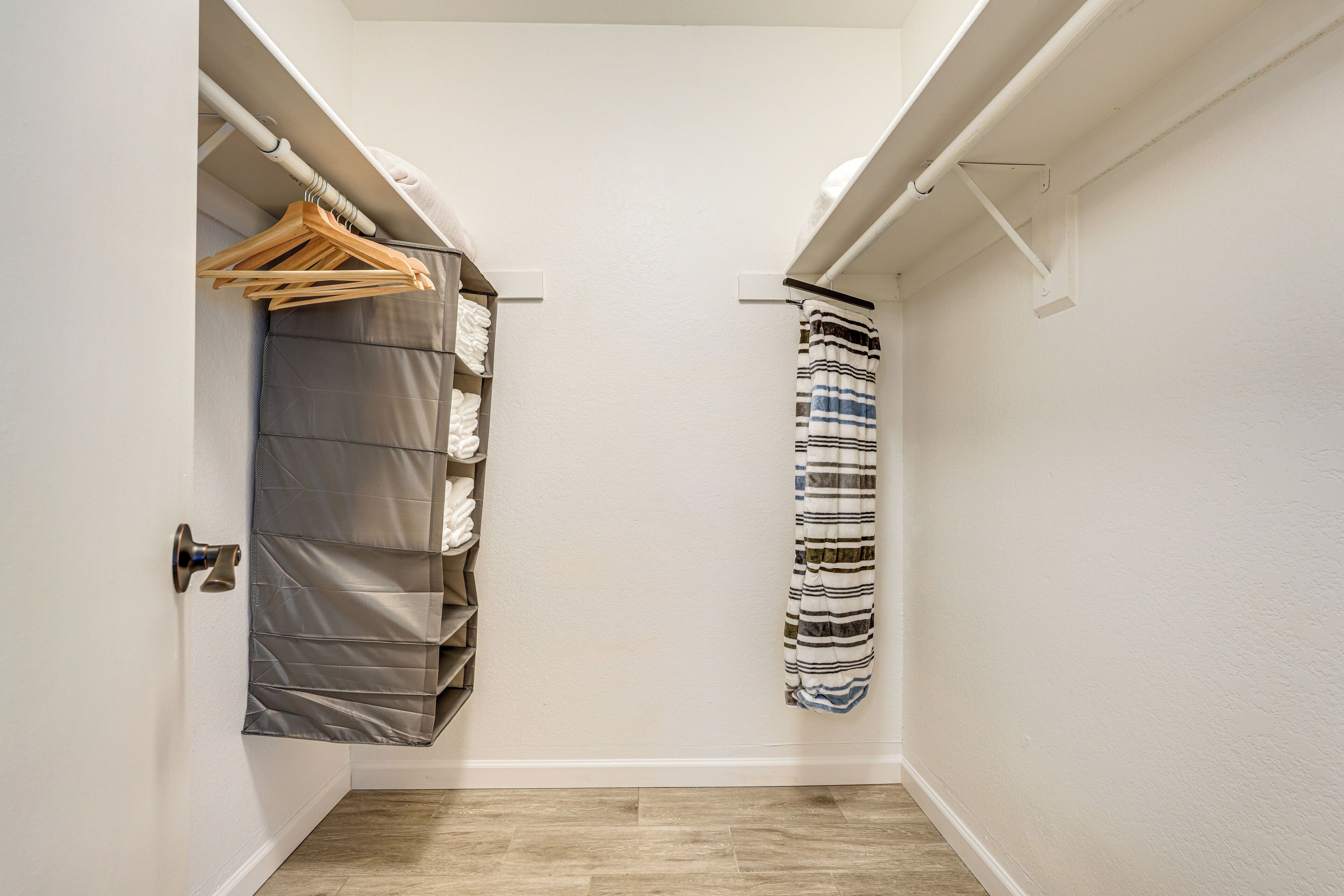 A narrow hallway with a built-in closet on one side, featuring a hanging rack and a folded storage unit.