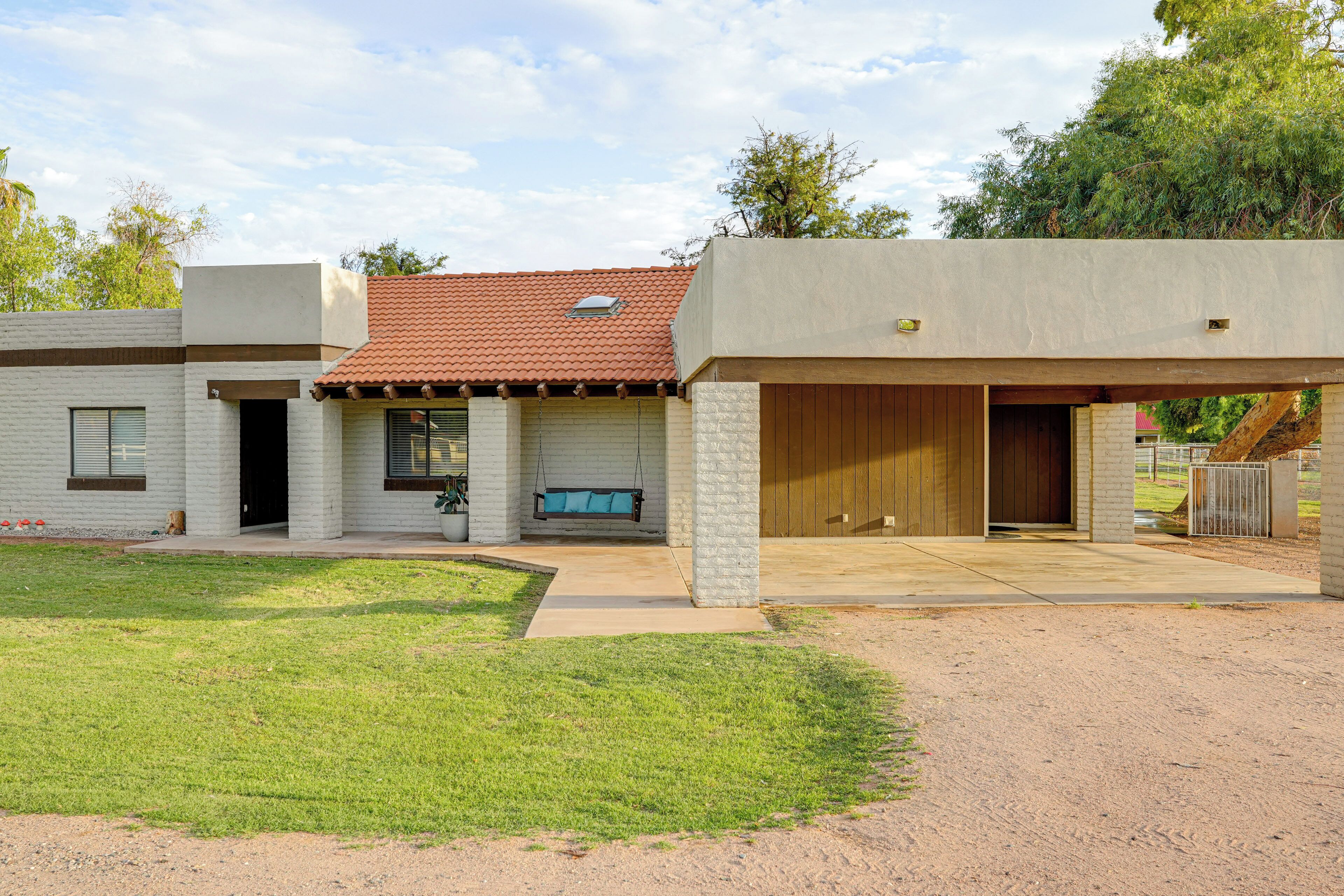 Une maison moderne dotée d’un patio couvert, d’une balançoire et d’un garage.