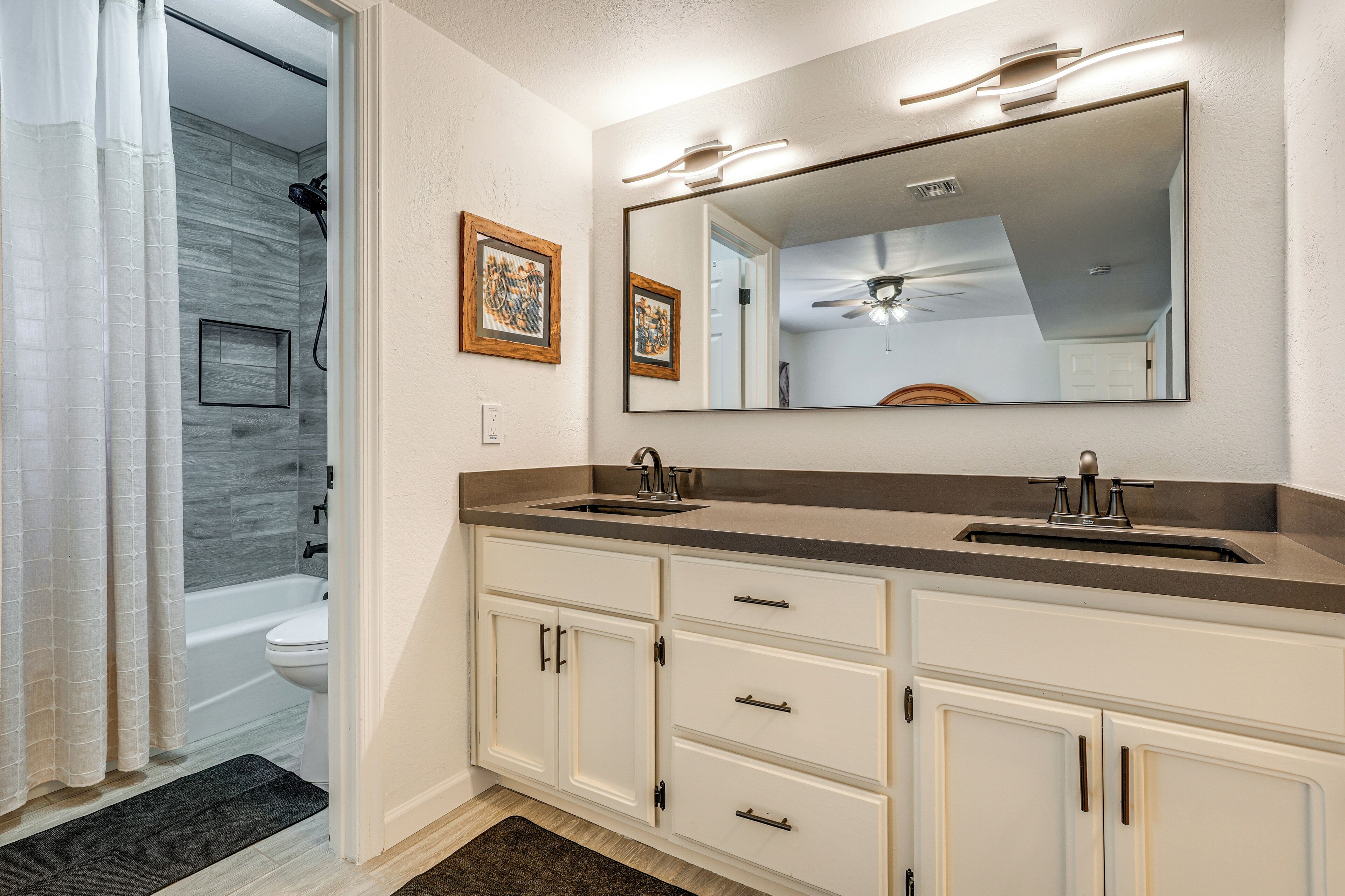 A bathroom with a double sink, vanity, and a shower area.