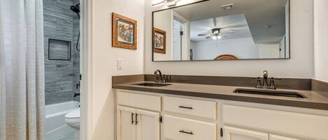 A bathroom with a double sink, vanity, and a shower area.