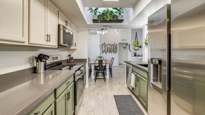 A modern kitchen with light green cabinets, stainless steel appliances, and a central island. - Family Home on > 2 Acres w/ Stables in Gilbert! (Gilbert)