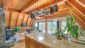 A spacious kitchen with a large island, wooden ceiling beams, and hanging pots.