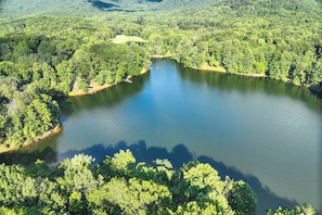 An aerial view of a lake surrounded by dense forest, with a small building visible near the water's edge. - Hot Tub, Decks & 2 Kitchens: Mtn-view Jasper Gem! (Jasper)
