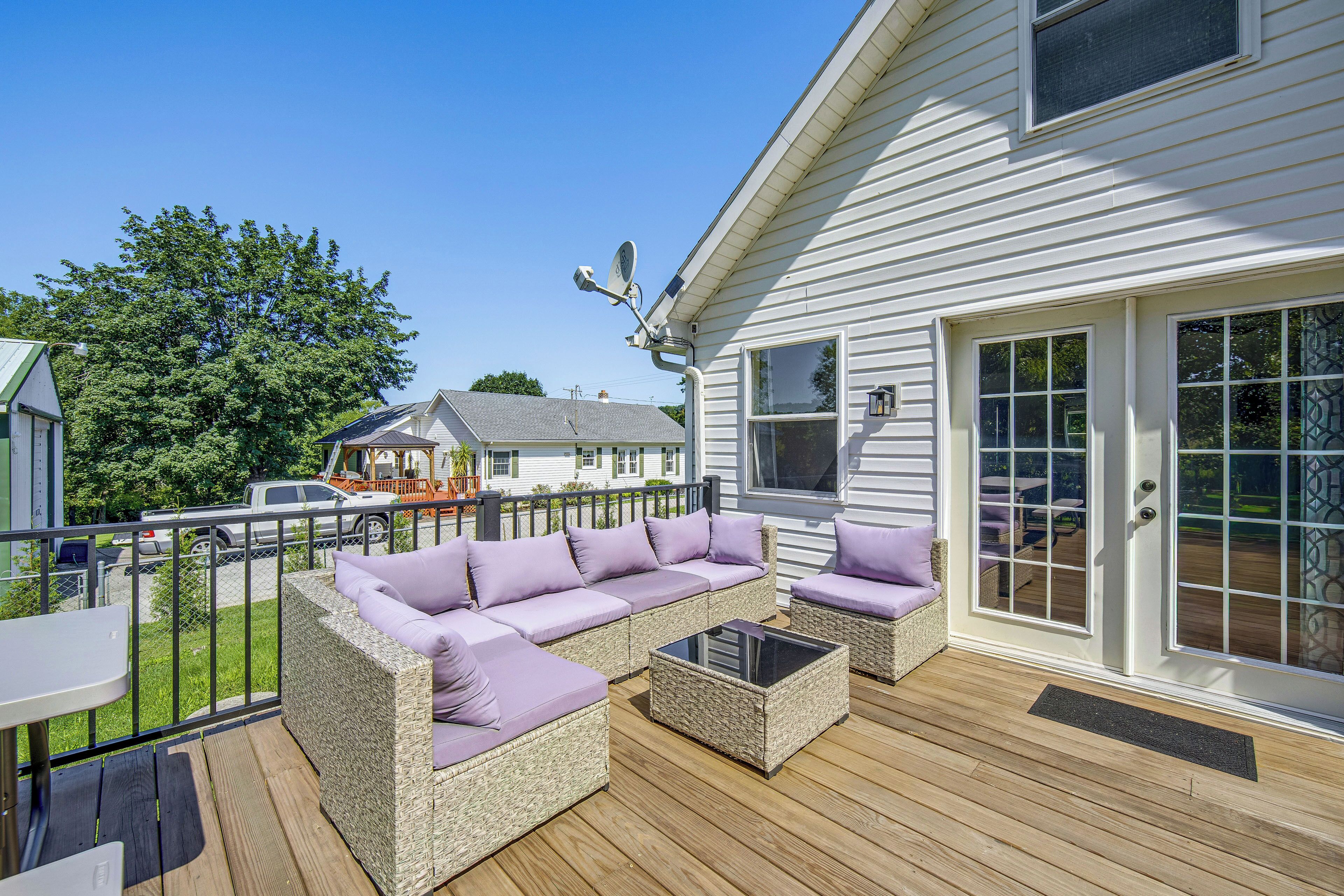 A covered outdoor deck with wicker furniture and a glass table.