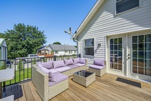 A covered outdoor deck with wicker furniture and a glass table. - York Farmhouse Hideaway Near Lake Redman (York)