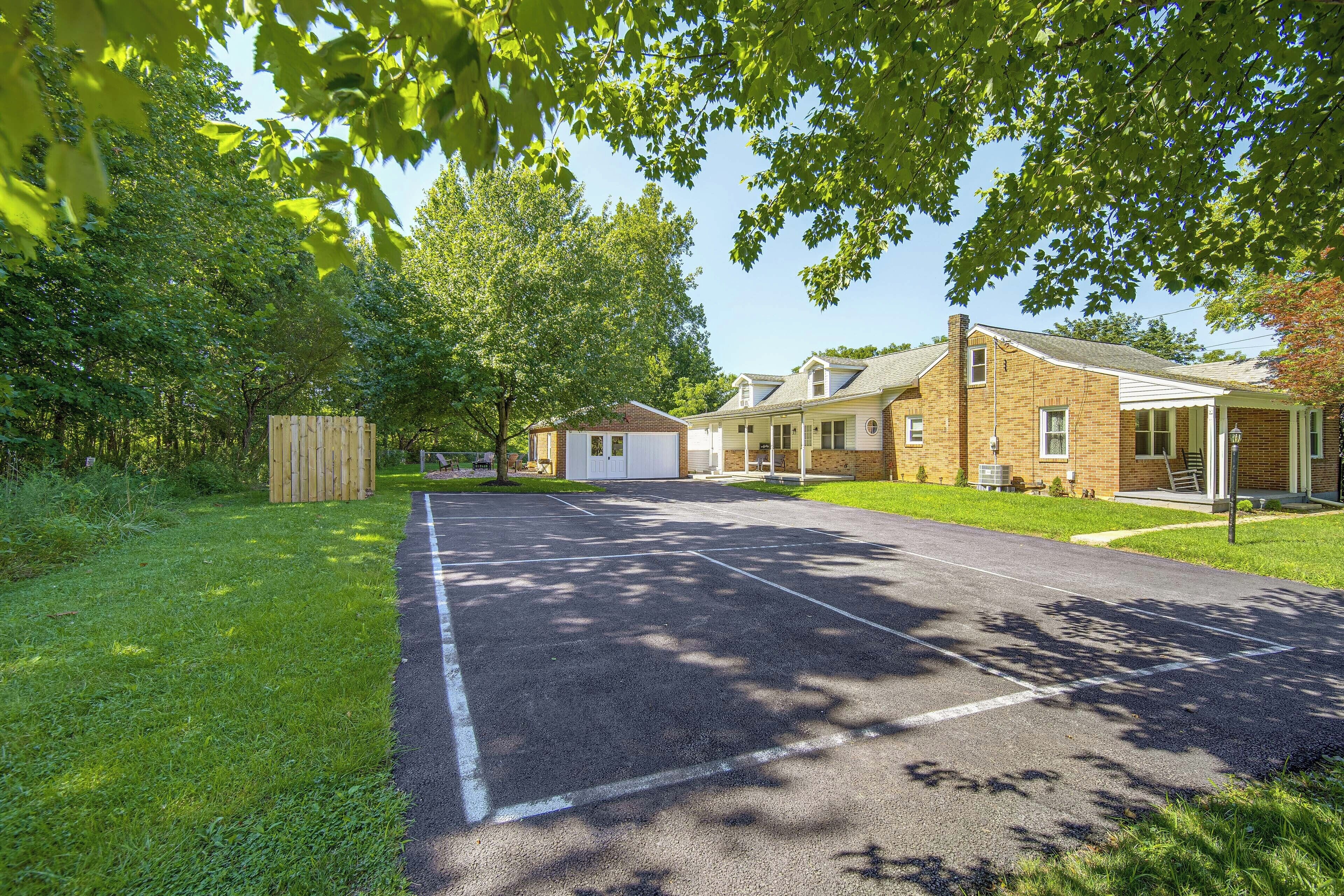 A residential street with a paved driveway, a garage, and a brick house with a porch.