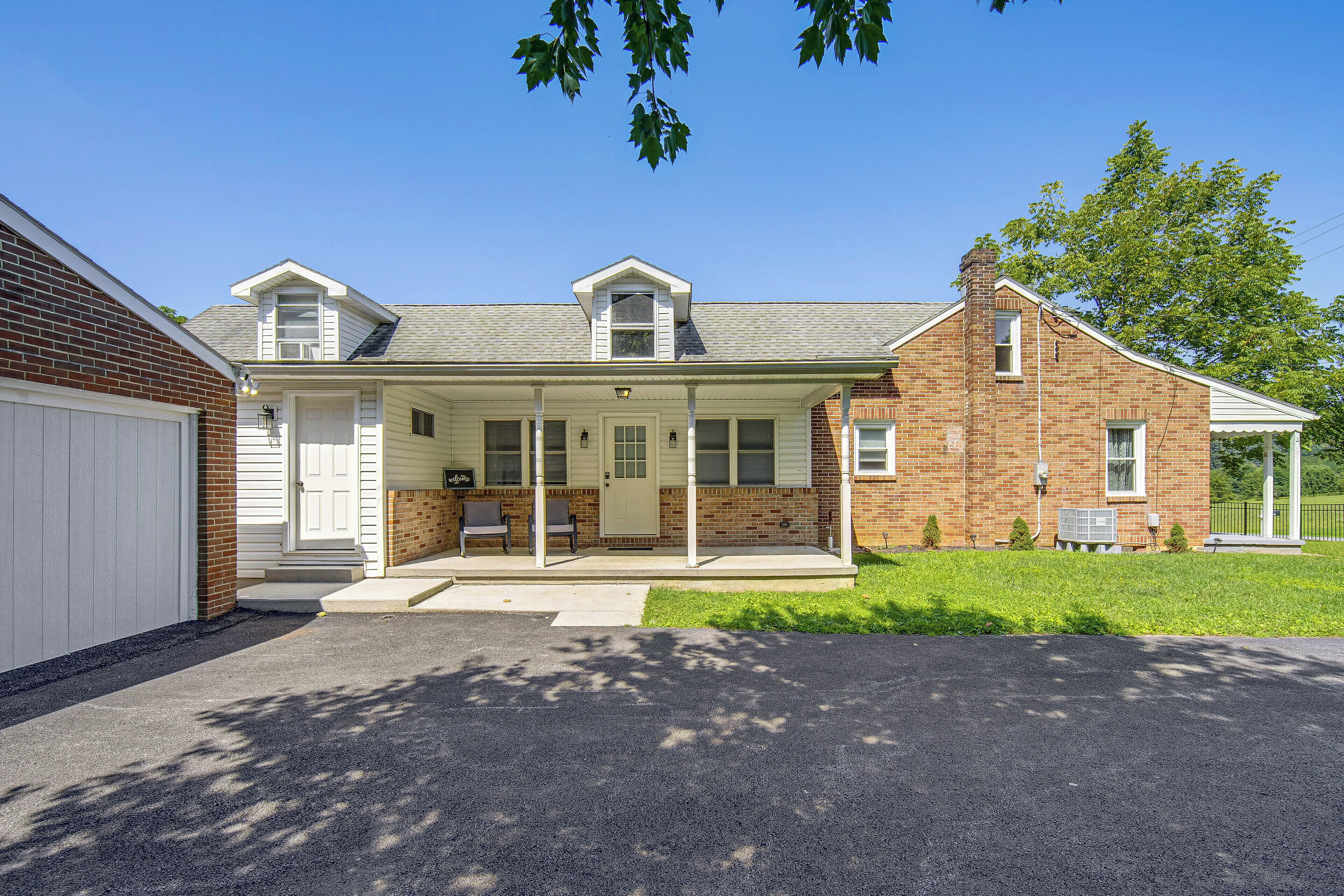 A two-story house with a covered porch, a garage, and a brick chimney.
