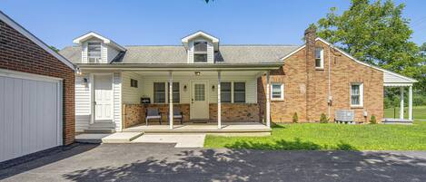 A two-story house with a covered porch, a garage, and a brick chimney.