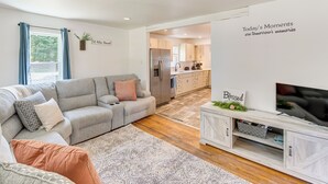 A modern living room with a grey sofa, a patterned rug, and a TV on a wooden cabinet. - York Farmhouse Hideaway Near Lake Redman (York)
