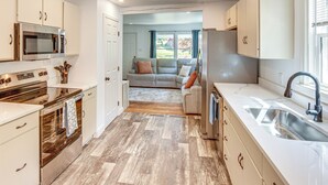 A modern kitchen with stainless steel appliances, a large sink, and a view to a living area. - York Farmhouse Hideaway Near Lake Redman (York)