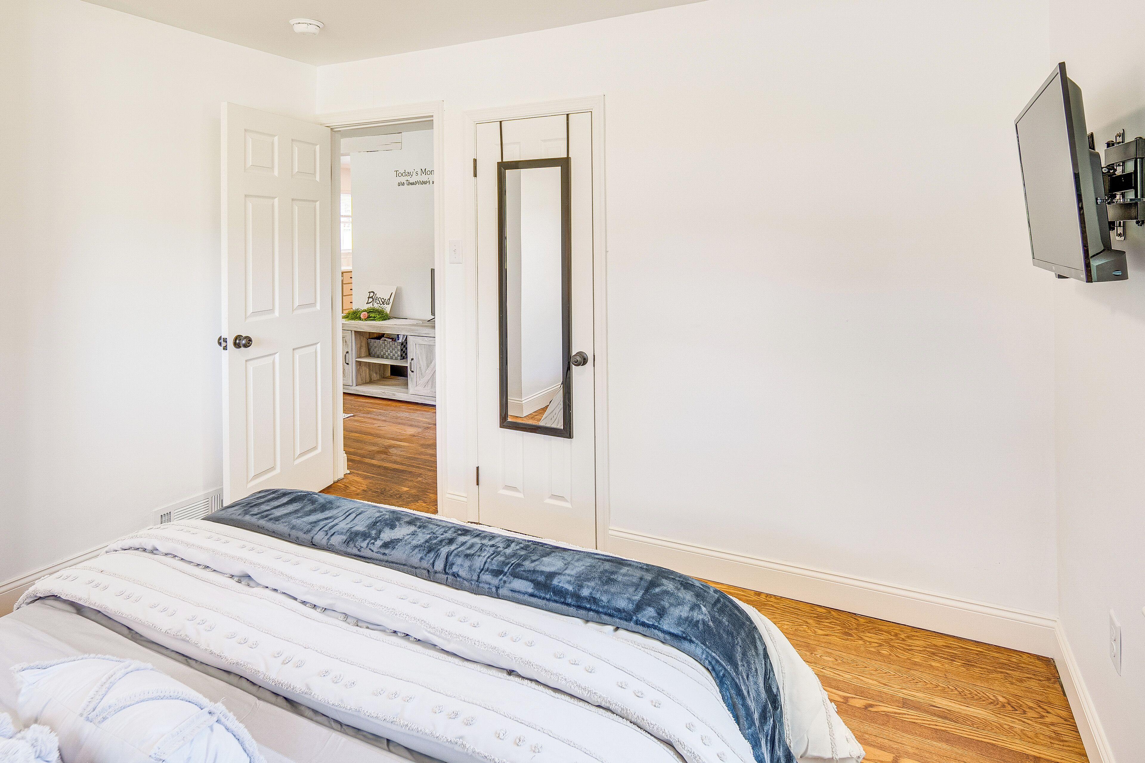 Un dormitorio con cama, una puerta que da a otra habitación y un televisor de pared.