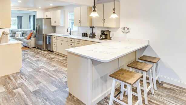 A modern kitchen with a central island, bar stools, and a dining area. - York Farmhouse Hideaway Near Lake Redman (York)