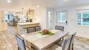 A modern kitchen with a central island, a dining area with a wooden table and chairs, and a view of the backyard through a window. - York Farmhouse Hideaway Near Lake Redman (York)