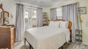 A bedroom with a large bed, a dresser, a vanity with a mirror, a chandelier, and a window with curtains. - Hot Tub & Fenced Yard: Cozy Cottage Grove Home (Cottage Grove)