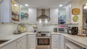 A modern kitchen with white cabinetry, a stainless steel oven, a microwave, and various kitchen appliances. - Hot Tub & Fenced Yard: Cozy Cottage Grove Home (Cottage Grove)