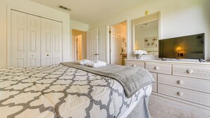 A bedroom with a large bed, a dresser, a television, and a mirror. - Townhouse in Lake Berkley Resort! 5 Mi to Old Town (Kissimmee)