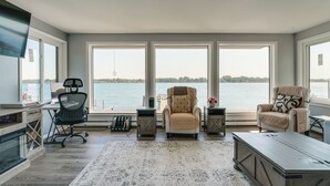 A spacious living area with a large window overlooking a body of water, a comfortable seating area, and a kitchen with modern appliances. - Spacious Riverfront Home w/ Dock in St Clair! (St. Clair)