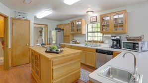 A modern kitchen with wooden cabinets, a central island, stainless steel appliances, and a view of the outdoors. - Wraparound Porch: Toledo Bend Reservoir Retreat! (Hemphill)